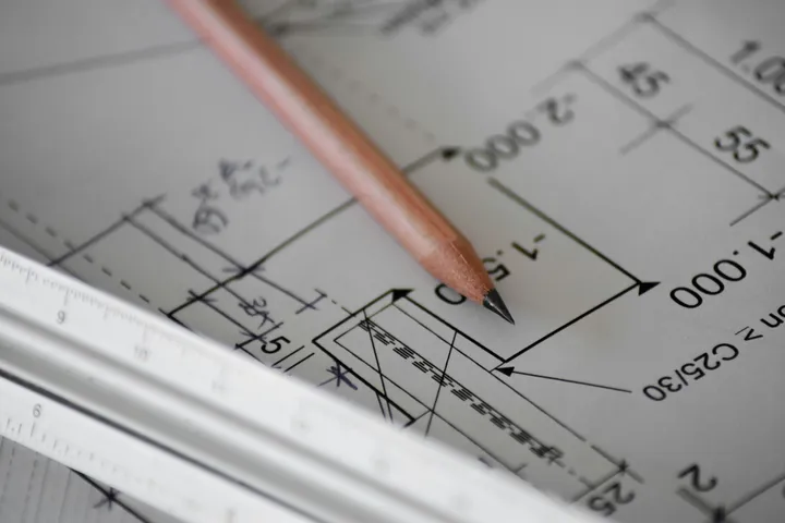 A pencil and ruler sitting on top of blueprints or schematics