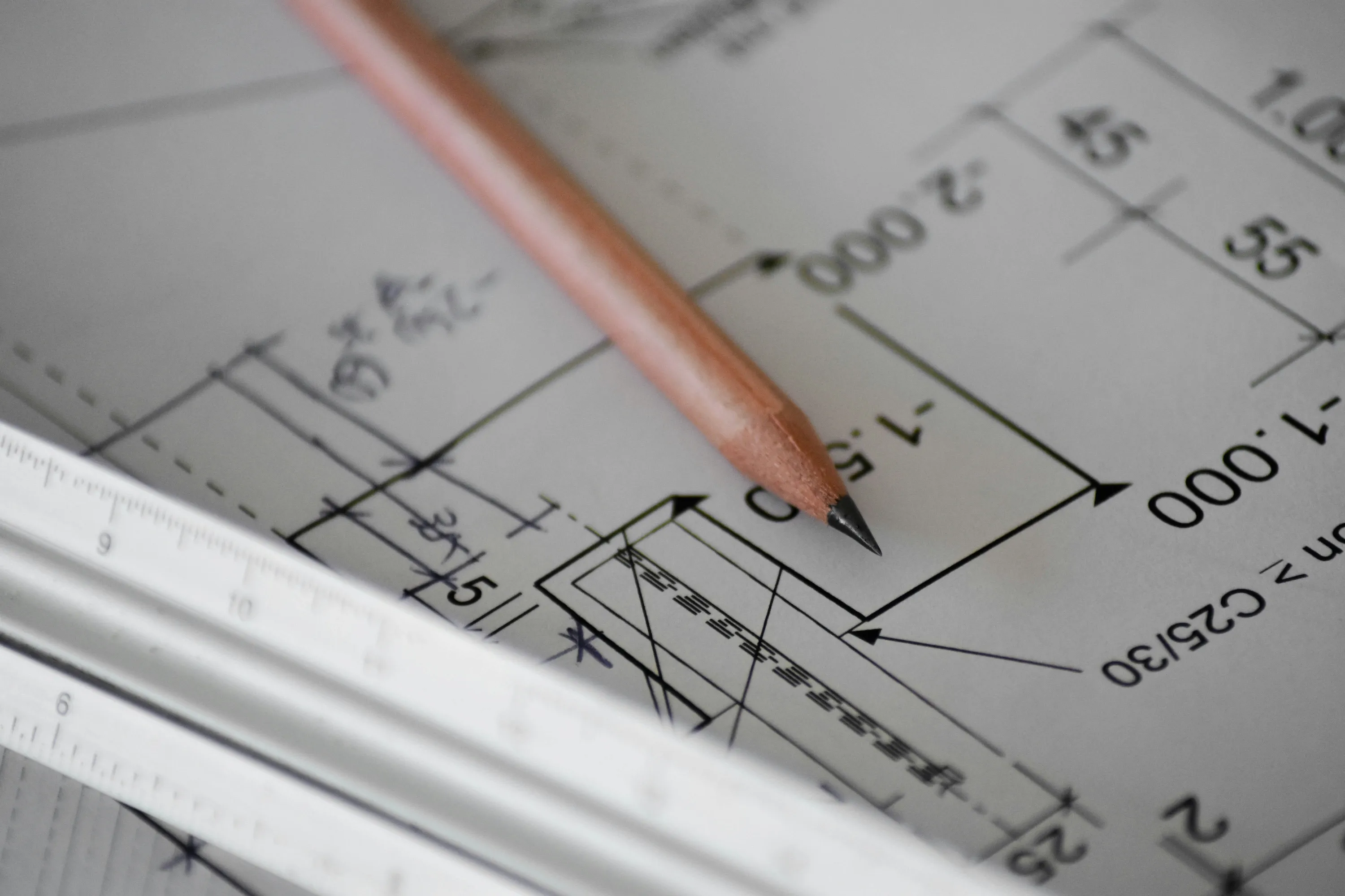 A pencil and ruler sitting on top of blueprints or schematics